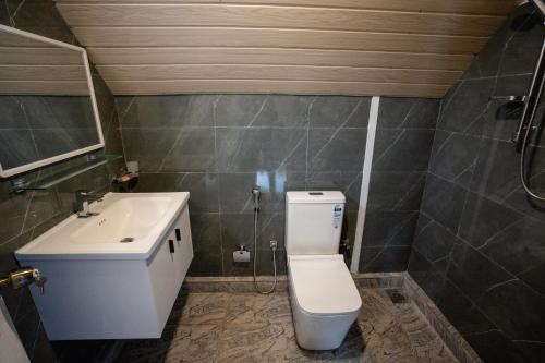a bathroom with a white toilet and a sink at The Tranquil Cabana - kandy in Rattanadeniya