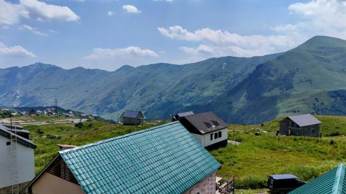 un groupe de maisons sur une colline avec des montagnes en arrière-plan dans l'établissement Gudauri Private Cottage 2, à Goudaouri