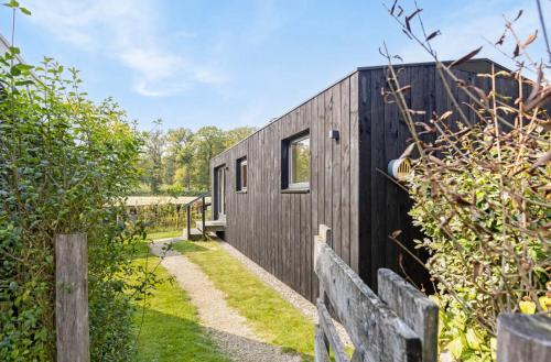 a small black house with a wooden fence at Chalet "naast de Schoppe" in Aalten