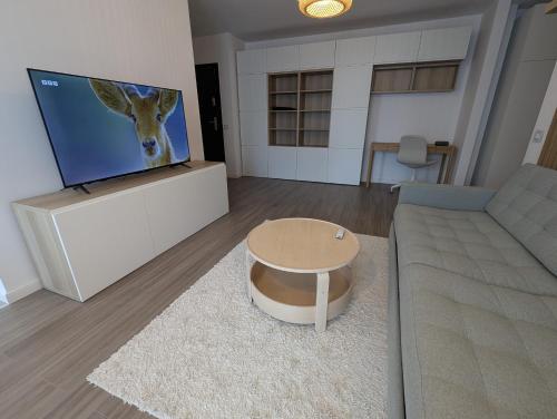 a living room with a couch and a tv with a deer on the screen at Apartament Elite in Cluj-Napoca