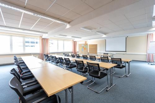una clase con mesas y sillas y una pizarra en Hermes Hotel Oldenburg, en Oldenburg