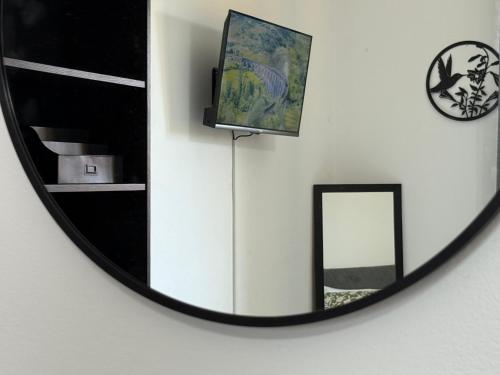 a mirror on a wall with a television and a clock at Orlandi Elegant Apartment in Bologna