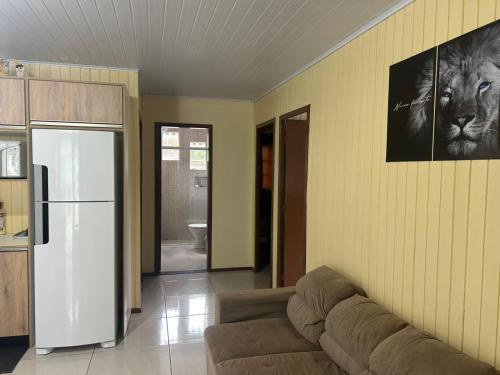 a living room with a couch and a refrigerator at Casa Alegria com Piscina in Barracão