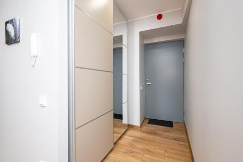 a hallway with white walls and a door and wood floors at Brand new Kalma Apartments in Tallinn