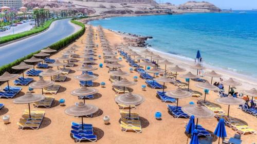 Una playa con sillas y sombrillas y el océano. en Porto Elsokhna, en Ain Sokhna