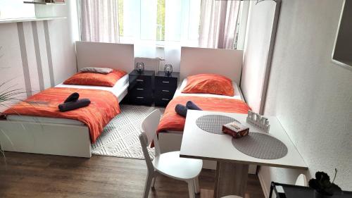 - 2 lits dans une chambre avec une table et un bureau dans l'établissement City Appartements Mainz, à Mayence