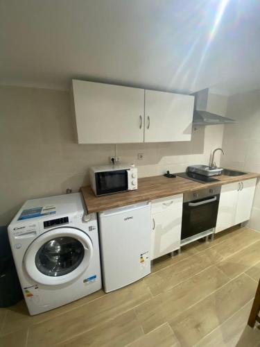 a kitchen with a washing machine and a microwave at Casa Eliza in Aldeia das Dez