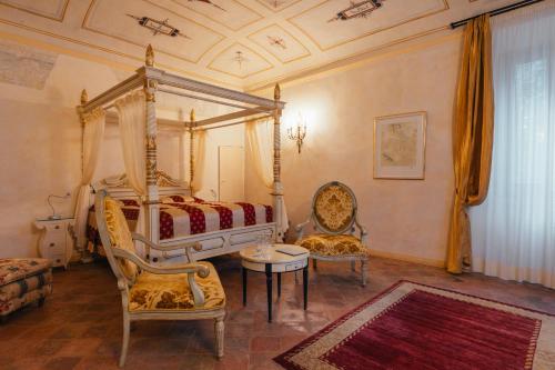 a bedroom with a canopy bed and two chairs at Villa Liverzano in Brisighella