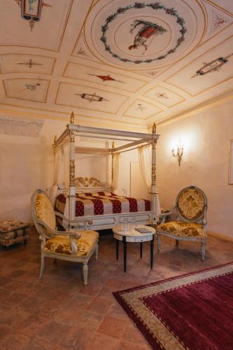 a bedroom with a canopy bed and two chairs at Villa Liverzano in Brisighella
