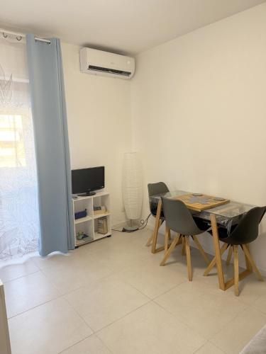 a living room with a table and chairs and a television at A BettyHouse in Quartu SantʼElena