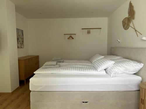 a bedroom with a bed with white sheets and pillows at Living OH43 in Illmitz