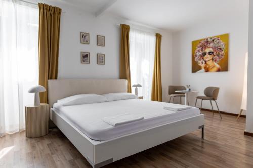 a white bedroom with a bed and a table at Easy Stay by Hotel La Perla in Ascona