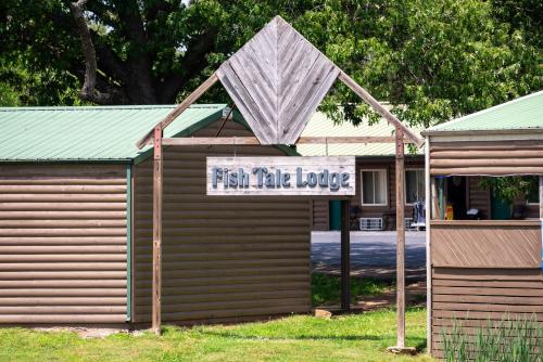 a sign on the side of a building with a sign for a fish take love at Fishtale Lodge Cabins in Buchanan