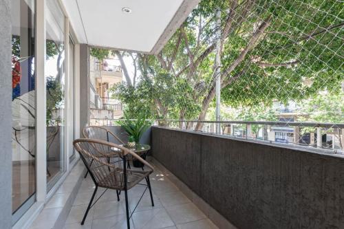einen Balkon mit einem Stuhl und einem Baum in der Unterkunft Fliphaus Gregoria Perez 3500 'A' - 1 Bd Patio & BBQ Colegiales in Buenos Aires
