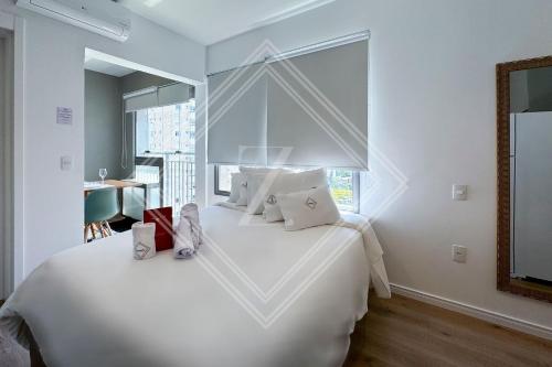 a bedroom with a large white bed with a window at Zainalofts7Vila Mariana ao lado metrô, CASV 117 ID in Sao Paulo
