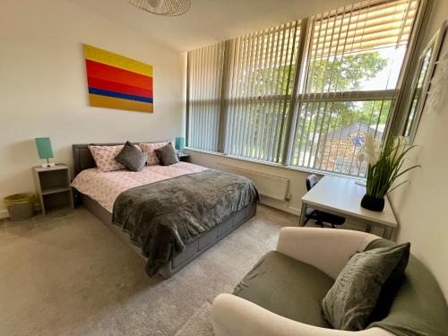 a bedroom with a bed and a chair and a couch at 2 Bedroom Flat Oak in Town Center Wellingborough in Wellingborough