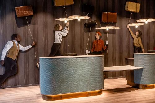 a group of people jumping on umbrellas in a room at Motel One Paris-Porte de Versailles in Issy-les-Moulineaux