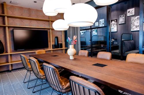 a conference room with a large wooden table and chairs at Motel One Paris-Porte de Versailles in Issy-les-Moulineaux