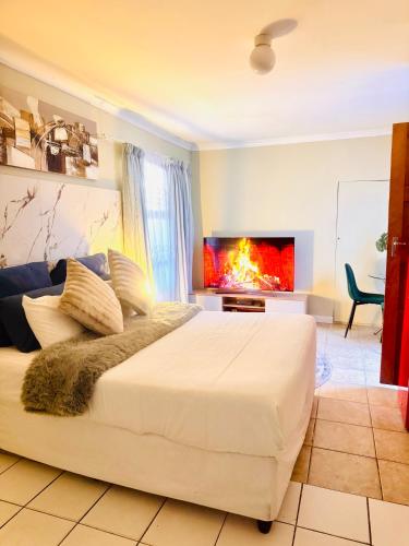 a bedroom with a large white bed and a fireplace at Greens Haven, Your Private escape in Cape Town in Cape Town