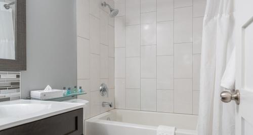 a white bathroom with a tub and a sink at Prestige Oceanview Hotel Prince Rupert in Prince Rupert