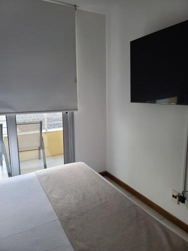 a bedroom with a bed and a flat screen tv at Apart Altos del Virrey in Colonia del Sacramento