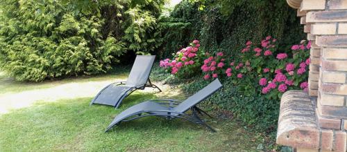 two lawn chairs sitting in the grass next to flowers at Maison rénovée dans le bocage Normand avec jacuzzi in Canisy
