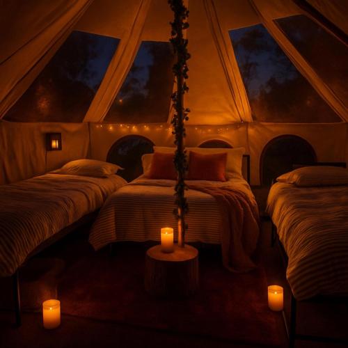 a room with three beds in a tent with candles at Cozy bell tent with heating and smart Tv in Llanfairpwllgwyngyll
