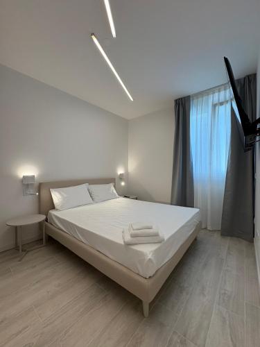 a white bedroom with a bed and a window at Residence Corallina in Caorle