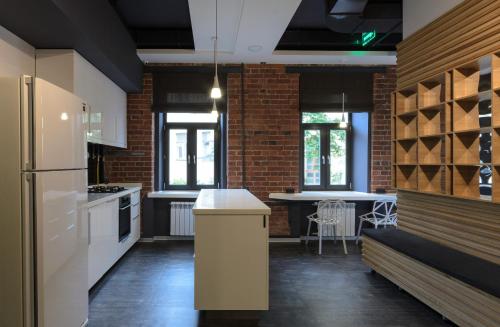 a kitchen with white appliances and a brick wall at Capsule Hotel Capsula in Moscow