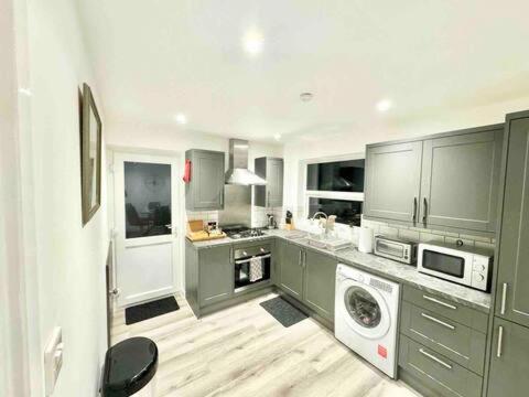 a kitchen with gray cabinets and a washing machine at Swindon Large 3 Bedroom house Parking, Garden in Swindon