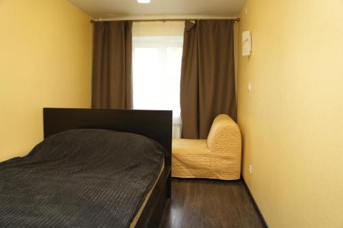 ヴェリーキー・ノヴゴロドにあるDesyatinnaya Apartmentのベッドルーム1室(ベッド1台、椅子、窓付)