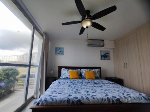 a bedroom with a ceiling fan and a bed with yellow pillows at PH Las Islas Punta Barco Viejo a 3 min de Coronado in San José