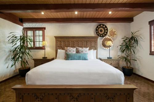 a bedroom with a large white bed and two plants at Rancho Caymus Inn in Rutherford