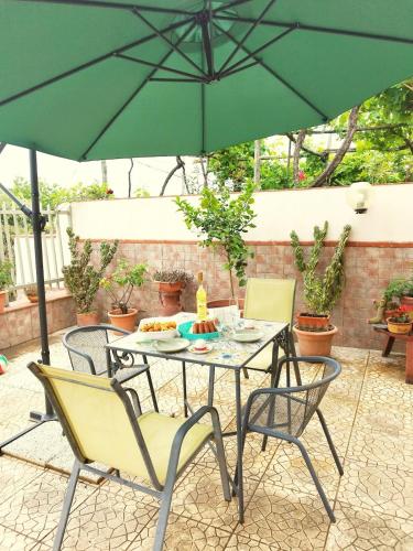 a table and chairs under an umbrella on a patio at La Casa nel Verde, tra mare e Vesuvio in Boscotrecase