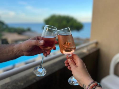 zwei Personen mit Weingläsern auf dem Balkon in der Unterkunft Appartement T2 Bord de Mer - Maria Beach in Santa-Lucia-di-Moriani