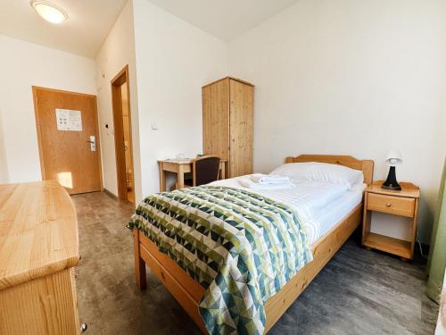 a bedroom with a bed and a wooden dresser and a bed sidx sidx sidx at Hotel Velká Klajdovka in Brno