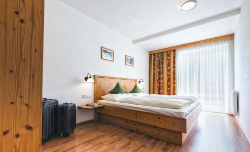 Schlafzimmer mit einem Bett mit einem Kopfteil aus Holz und einem Fenster in der Unterkunft Apparthotel AlpenChalet in Neukirchen am Großvenediger