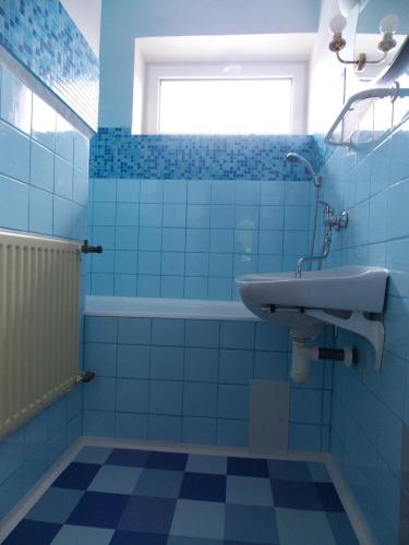 a blue tiled bathroom with a sink and a tub at Penzion Babička, pokoj A in Trojanovice
