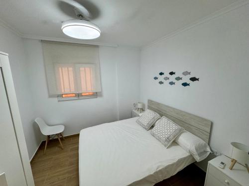 a white bedroom with a bed and a window at El Raconet d'Emma in Bellreguart