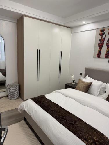 1 dormitorio con 1 cama grande y armarios blancos en City homes, en Nairobi