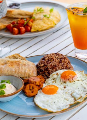 a blue plate of breakfast food with eggs and bread at Amaka Ocean Living Lodge in Golfito