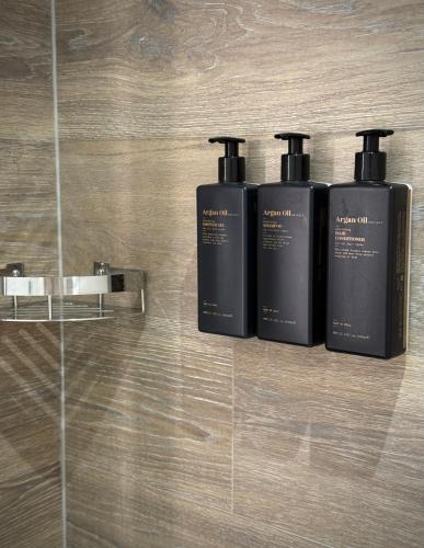three black shampoo bottles sitting on a wall at Hotel Ponta Plaza Conference & Spa in Budva