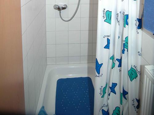 a bathroom with a bath tub with a shower curtain with fish on it at Weingut Wissler - Brennerei in Au