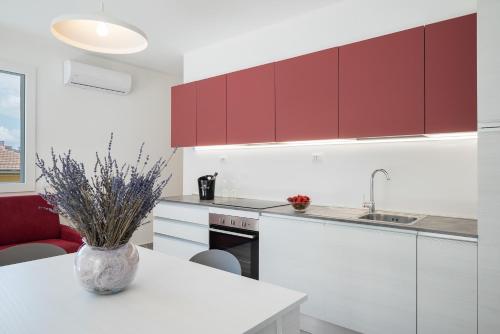 a kitchen with red cabinets and a table with a vase at Hotel La Pineta in Follonica