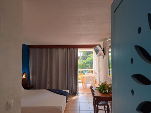 ein Schlafzimmer mit einem Bett und einem Tisch und einem Fenster in der Unterkunft Studio Capucine in Sainte-Anne