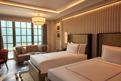a hotel room with two beds and a couch at Fairmont Mumbai in Mumbai
