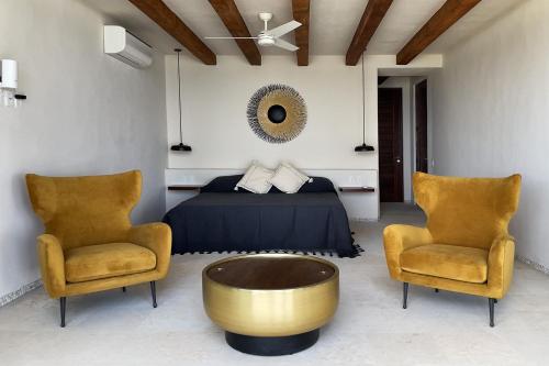 a bedroom with a bed and two chairs at Casa Celeste in Troncones