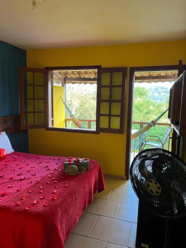 a bedroom with a red bed and two windows at Villa Macacos in Nova Lima