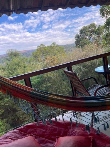 a hammock with two chairs and a table on a balcony at Villa Macacos in Nova Lima