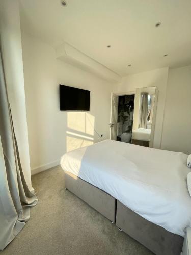 a white bedroom with a large bed and a flat screen tv at Stone Lodge 2 min Walk From Edgware Underground in Edgware